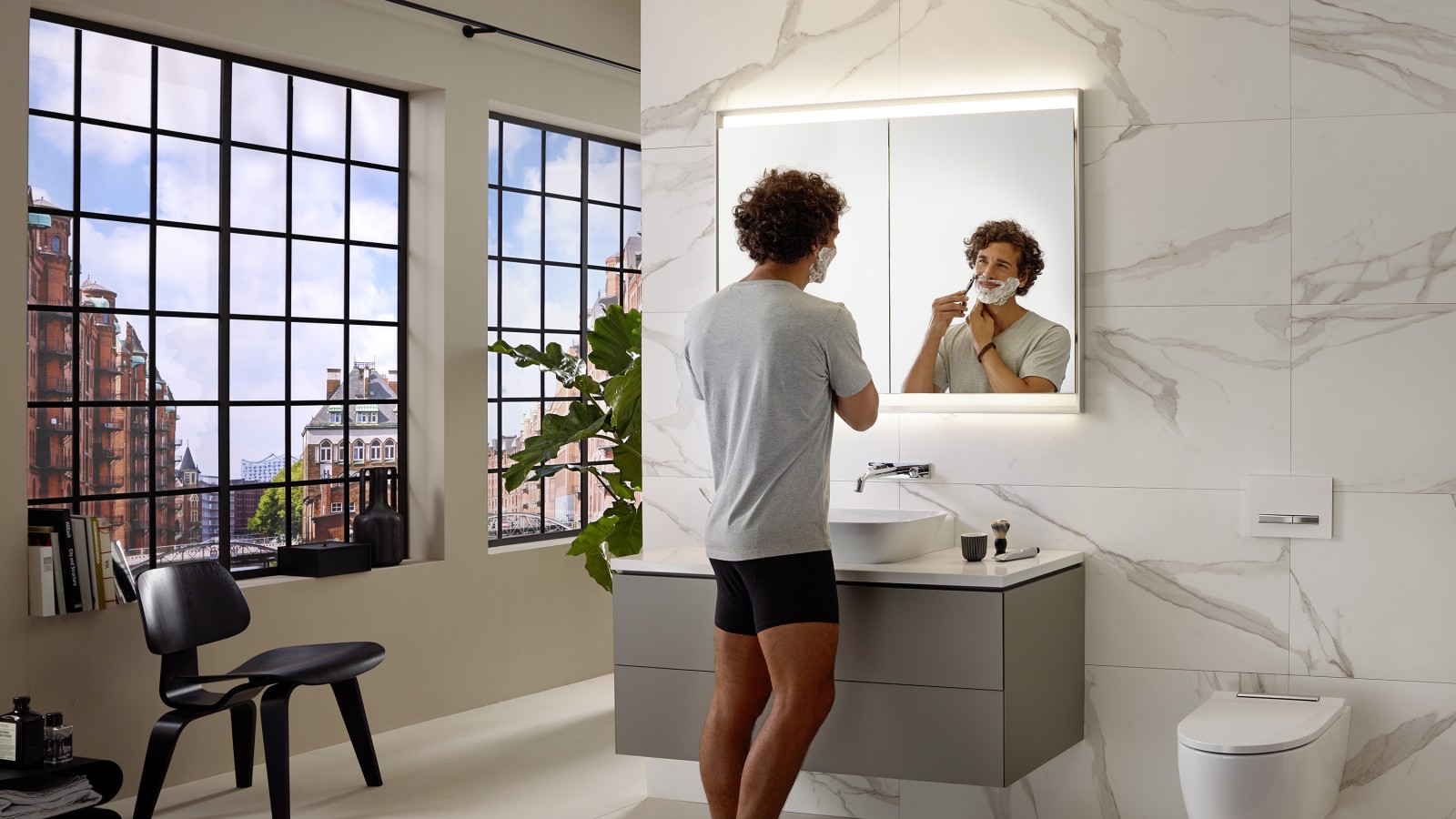 Man shaving at washbasin with Geberit ONE furniture and mirror cabinet