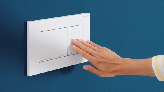 Hand triggers a flush on the white Sigma20 actuator plate (© Geberit) Hand triggers a flush on the white Sigma20 actuator plate (© Geberit)